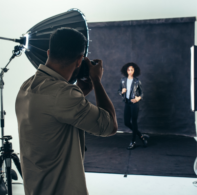 Photographe et modèle en veste noire pendant une séance photo en studio.